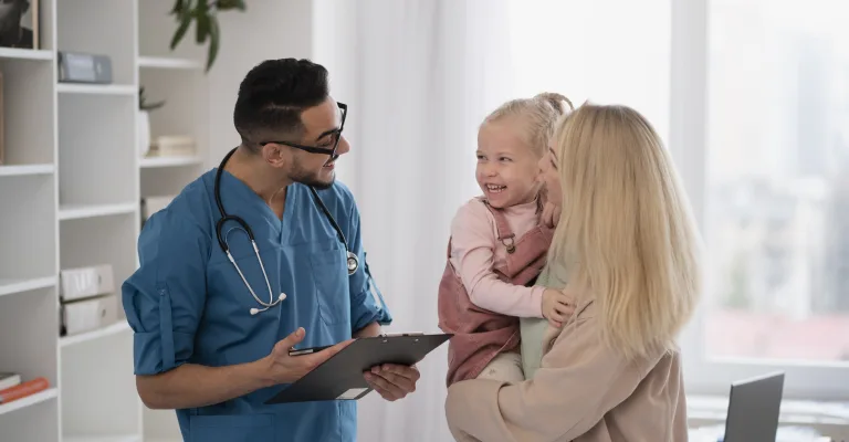 Medic discutând cu o mamă care își ține fetița în brațe