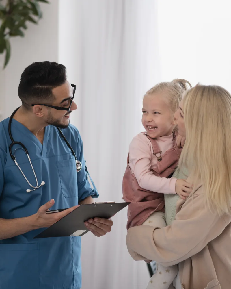 Medic discutând cu o mamă care își ține fetița în brațe